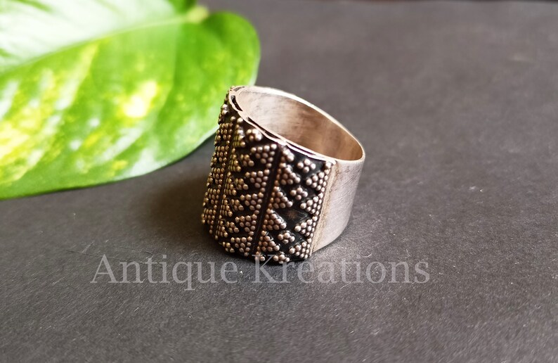K&ouml;nnte beinhalten: Ein silberner Ring mit geometrischem Muster. Der Ring ist breit und hat eine strukturierte Oberfl&auml;che.