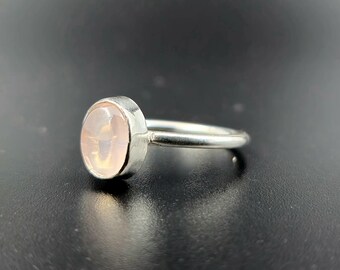 Puede incluir: Un anillo de plata con una piedra ovalada de color rosa pálido.