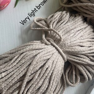 May include: A close-up of a large bundle of very light brown cotton rope. The rope is thick and has a natural, slightly textured appearance.