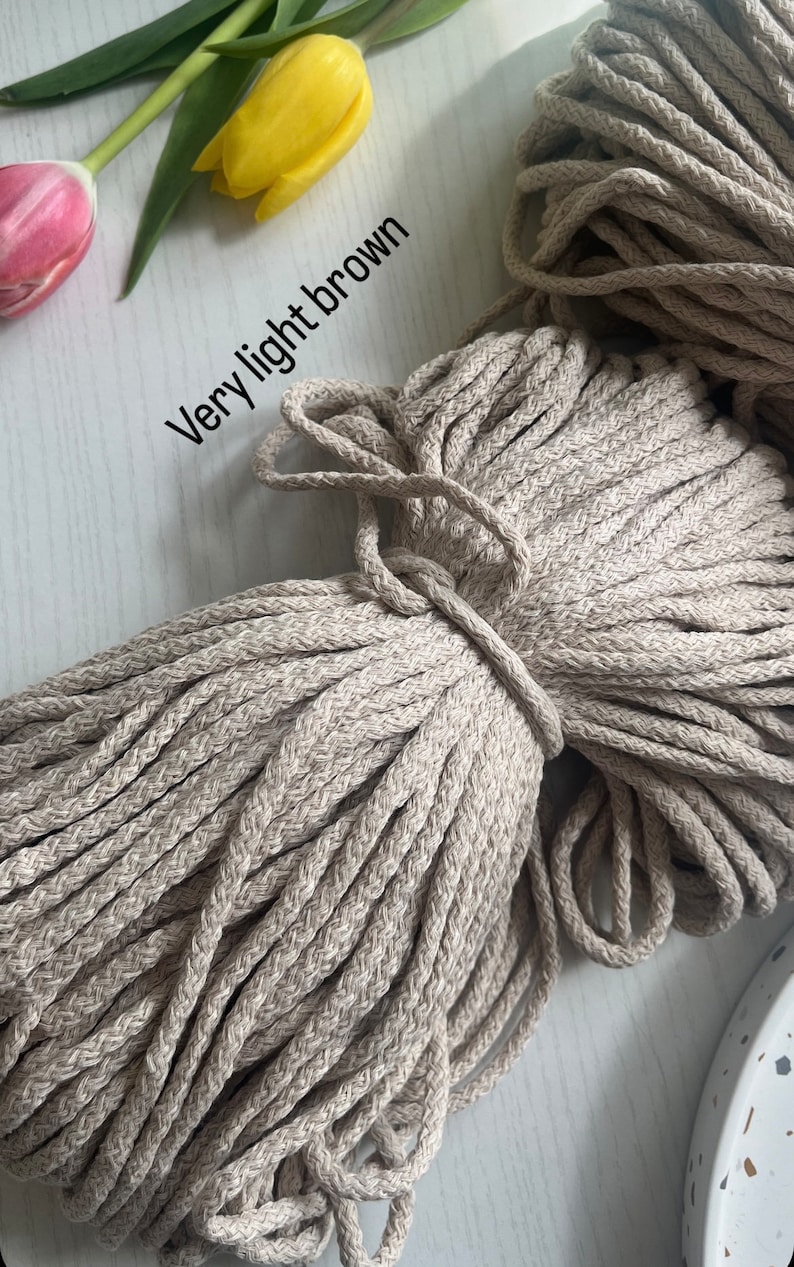 May include: A close-up of a large bundle of very light brown cotton rope. The rope is thick and has a natural, slightly textured appearance.