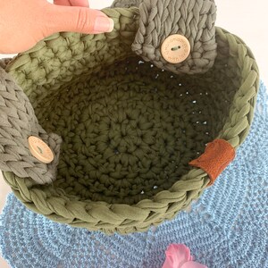 May include: A green crocheted basket with two fabric handles and wooden buttons that say "handmade with love".