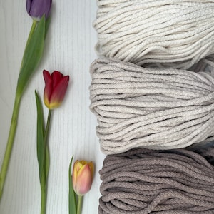 May include: Three spools of natural cotton rope in different colors: beige, light brown, and dark brown. The rope is thick and textured, perfect for crafting.