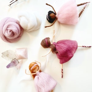 May include: Three handmade felt ballerina dolls in pink and burgundy dresses, with brown hair and delicate features. The dolls are posed in graceful ballet positions. Also shown are raw wool, crystals, and pussy willow branches.