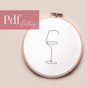 May include: A black and white line drawing of a wine glass on a white background. The drawing is in a wooden embroidery hoop.