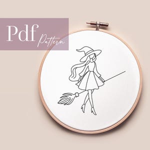 Könnte beinhalten: Eine Strichzeichnung einer Hexe auf einem Besen, gestickt auf weißem Stoff in einem hölzernen Stickrahmen. Die Hexe trägt einen spitzen Hut und ein Kleid. Der Text "Pdf Pattern" befindet sich oben links.