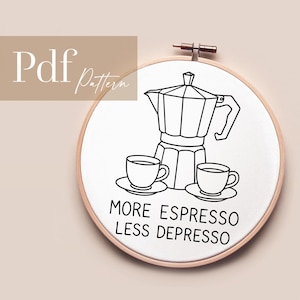 Könnte beinhalten: Stickrahmen mit weißem Stoff, der eine schwarze Strichzeichnung einer Espressokanne und zwei Kaffeetassen zeigt. Der Text "MORE ESPRESSO LESS DEPRESSO" steht unter den Kaffeetassen. Die Worte "Pdf Pattern" stehen oben links.