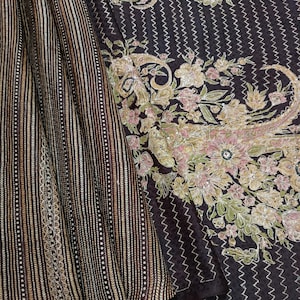 Puede incluir: Un sari de seda marrón con bordados dorados y plateados. El sari tiene un patrón floral y un borde a rayas.