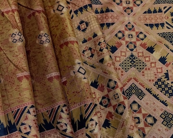 May include: A fabric textile featuring a repeating geometric pattern in shades of gold, navy blue, and muted red. The design consists of intricate squares, diamonds, and linear motifs arranged in a structured grid, with folds creating depth.