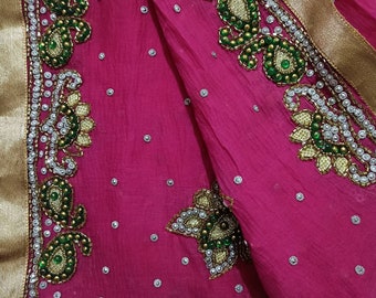 May include: A pink fabric with a gold border and intricate green and silver embroidery. The embroidery features paisley patterns and floral designs.