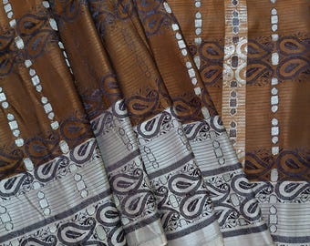 May include: A brown textile with intricate paisley and striped patterns. The fabric has a metallic sheen, with silver and dark blue accents. The design includes a border with detailed paisley motifs and a striped central section.