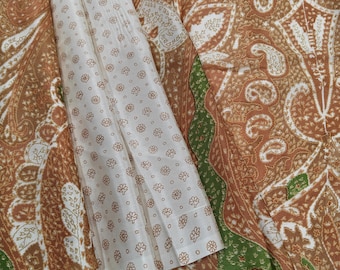 May include: A textile fabric featuring a large-scale paisley pattern in shades of brown, white, and green. A contrasting section of the fabric displays a smaller, repeating floral print in brown on a white background, creating a distinct border.