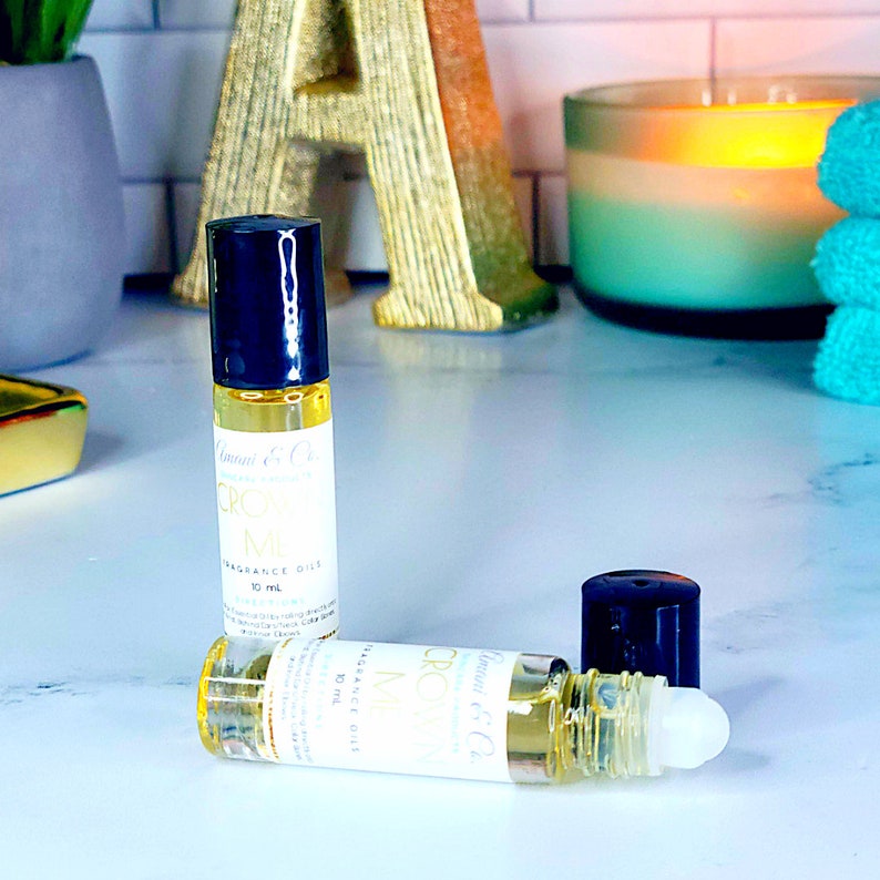 May include: Two clear glass roll-on bottles with black caps and gold accents. The bottles contain a yellow liquid and are labeled "Creamy Mint" and "Creamy Vanilla" with the text "Fragrance Oil 10 ml".