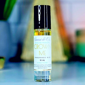 May include: A clear glass bottle with a black cap and a white label that says "Amani & Co. Skincare Products Crown Me Fragrance Oils 10 mL Directions Apply Essential Oil by rolling directly on Wrist, Behind Ears/Neck, Collar Bone and Inner Elbows."