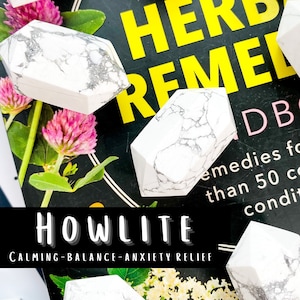 May include: White howlite crystals with gray veining are scattered on a book titled "Herbal Remedies." The crystals are hexagonal shaped. The text "HOWLITE" and "CALMING-BALANCE-ANXIETY RELIEF" are also visible.