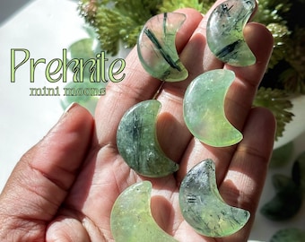 May include: Prehnite mini moon crystals in shades of green and translucent clarity. The crescent-shaped stones have dark inclusions, and the text "Prehnite mini moons" is visible in the image.