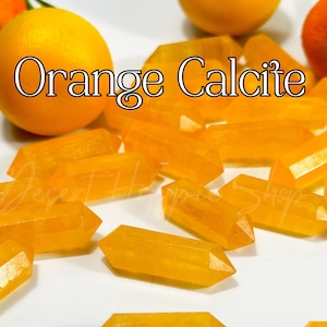 Puede incluir: Cristales de calcita naranja de varios tamaños y formas. Los cristales son de un color naranja vibrante y tienen un acabado brillante. Los cristales están dispuestos sobre una superficie blanca. El texto "Calcita Naranja" está escrito en letras blancas sobre fondo negro.