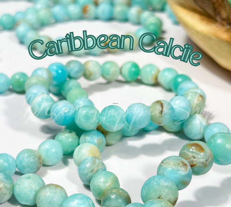 May include: Strands of Caribbean Calcite beads in shades of turquoise, light green, and cream. The beads are round and have a polished finish. The text "Caribbean Calcite" is superimposed on the image. These beads are suitable for jewelry making.
