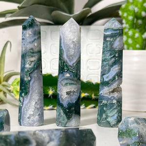 May include: A set of three ceramic mugs with a speckled, matte finish. The mugs are in shades of cream, light gray, and dark gray. Each mug has a simple, modern design and a rounded handle.