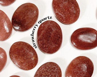 Op de afbeelding: Een verzameling gladde, ovale aardbeikwartsstenen. De stenen zijn diep roodbruin van kleur met een subtiel sprankelen. De tekst "aardbeikwarts" is in het zwart over de afbeelding geschreven.