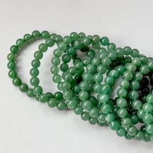 Puede incluir: Varias hebras de cuentas de piedras preciosas verdes. Las cuentas son redondas y tienen un acabado pulido y brillante. El color es un verde medio intenso. Las cuentas est&aacute;n ensartadas, formando collares o pulseras.