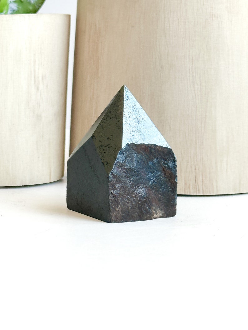 May include: A dark gray, pyramid-shaped crystal with a rough, textured surface.