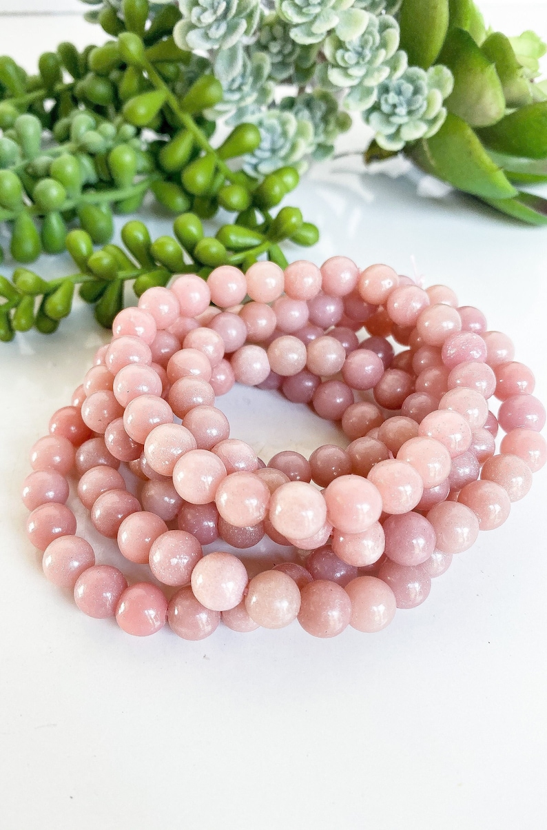 May include: A stack of pink opal bead bracelets. The beads are round and smooth, and the bracelets are made with elastic.