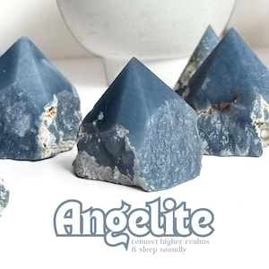 May include: A group of six blue-grey angelite crystal points, each with a unique shape and texture. The crystals are arranged on a white surface. The text "Angelite connect higher realms & sleep soundly" is written below the crystals.