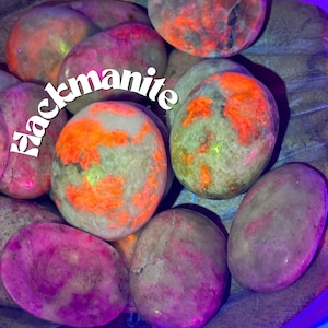 May include: A collection of polished blackmanite stones, featuring a variety of colors and patterns. The stones are smooth and have a natural, earthy look. The stones are arranged in a pile, with some overlapping. The stones are a mix of light and dark colors, with some having a reddish hue. The stones are all different sizes and shapes.