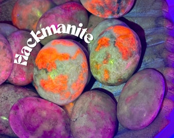 May include: A collection of polished blackmanite stones, featuring a variety of colours and patterns. The stones are smooth and have a natural, earthy look. The stones are arranged in a pile, with some overlapping. The stones are a mix of light and dark colours, with some having a reddish hue. The stones are all different sizes and shapes.