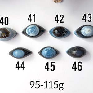 May include: Seven polished, eye-shaped stones labelled 40 through 46, each featuring unique blue, grey, and black patterns. The stones are arranged in two rows, with the text 95-115g displayed at the bottom, indicating their weight range.