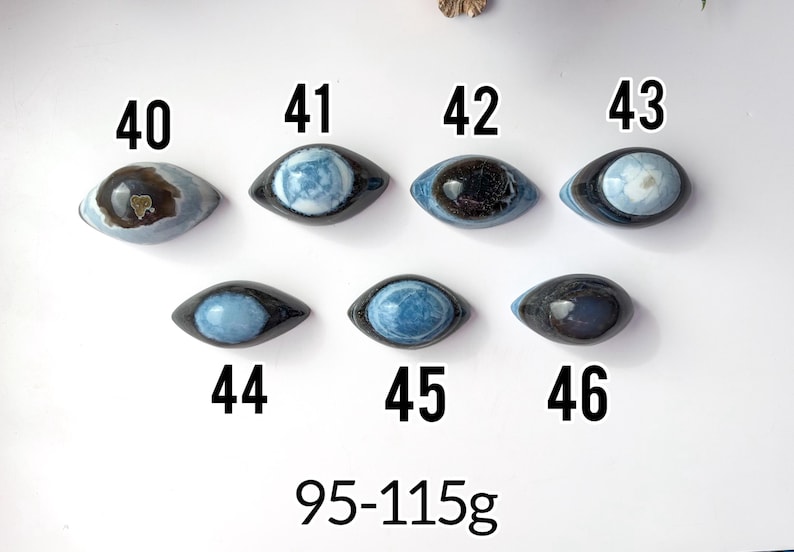 May include: Seven polished, eye-shaped stones labelled 40 through 46, each featuring unique blue, grey, and black patterns. The stones are arranged in two rows, with the text 95-115g displayed at the bottom, indicating their weight range.