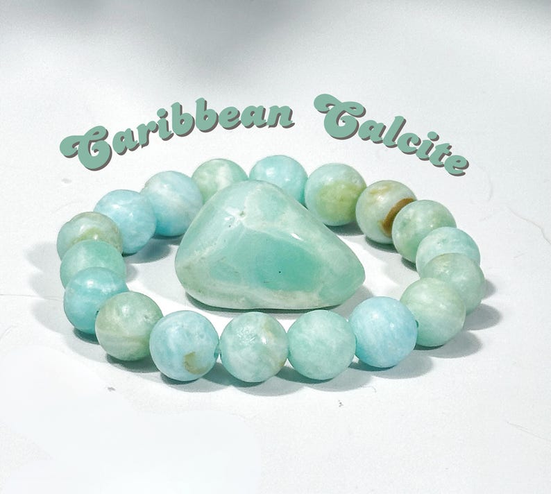 May include: A Caribbean Calcite bracelet with a large, polished stone in the center, surrounded by round beads. The beads and central stone are a mix of light blue and green hues. The words "Caribbean Calcite" are arched above the bracelet.