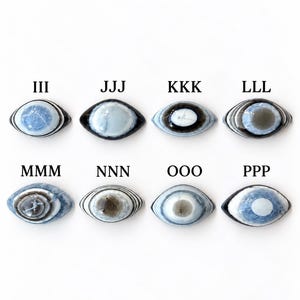 May include: Eight oval-shaped cabochons arranged in two rows, each featuring concentric eye-like patterns in shades of blue, grey, white, and black. Each stone is labelled with letters III, JJJ, KKK, LLL, MMM, NNN, OOO, and PPP above it.