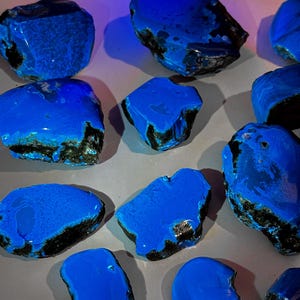 Puede incluir: Una colecci&oacute;n de piedras preciosas azules y negras. Las piedras son lisas y pulidas, con una variedad de formas y tama&ntilde;os.