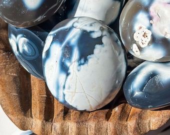 May include: A collection of polished agate stones with a variety of blue and white patterns. The stones are smooth and have a natural, organic look.