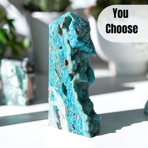 May include: A blue and white celestite crystal tower with a unique, organic shape. The crystal has a rough, textured surface and is a beautiful example of this mineral.