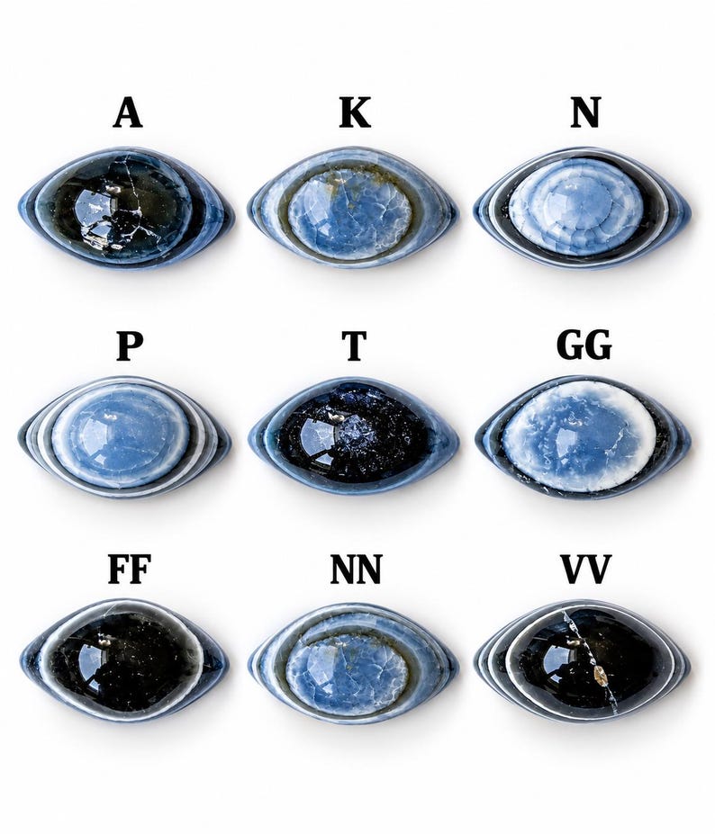 May include: Nine oval-shaped cabochons arranged in a grid, each featuring blue and black concentric patterns. The items are labelled with letters A, K, N, P, T, GG, FF, NN, and VV. Each piece displays a smooth, polished surface with unique variations in colour intensity and internal veining, resembling eye-like designs.