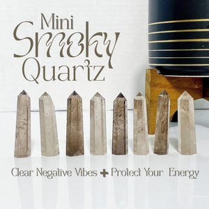 May include: Eight mini smoky quartz crystal points in shades of brown and grey. The crystals are displayed in a row, with the text "Mini Smoky Quartz" above and "Clear Negative Vibes + Protect Your Energy" below.