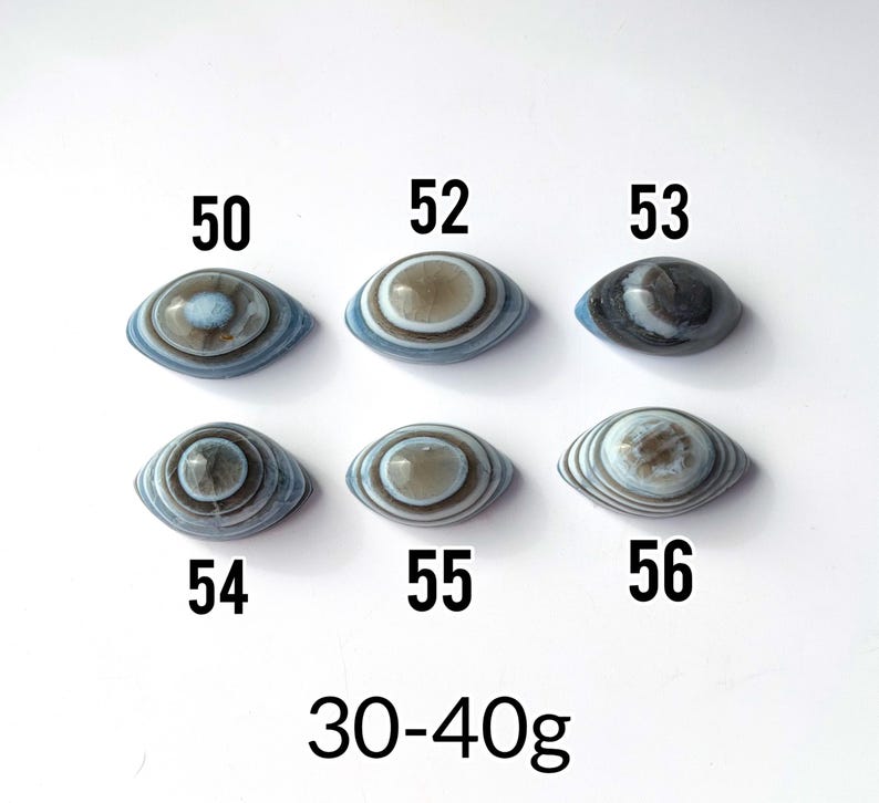 May include: Six oval-shaped banded agate stones arranged in two rows, labelled with numbers 50, 52, 53, 54, 55, and 56. Each stone features concentric circular patterns in shades of blue, grey, and white. The text 30-40g is printed at the bottom.