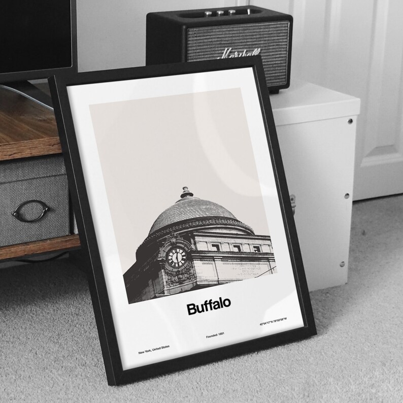 May include: Black and white photograph of a building with a clock tower in Buffalo, New York. The building is a historic landmark and is known as the Buffalo City Hall. The photo is framed in a black frame.