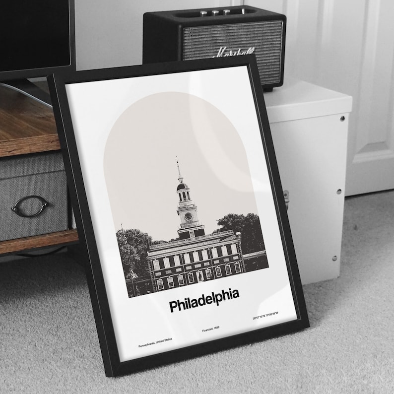 May include: Black and white illustration of Independence Hall in Philadelphia, Pennsylvania. The building is surrounded by trees and the text "Philadelphia" is printed below the image.