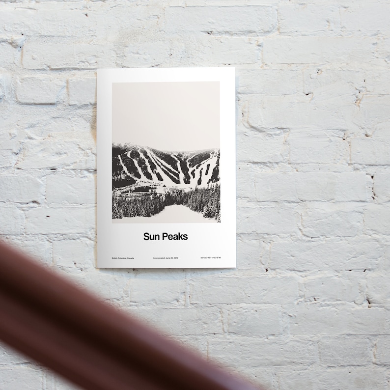 May include: A black and white photograph of a ski resort called Sun Peaks, located in British Columbia, Canada. The photo shows a mountain with ski runs and trees.