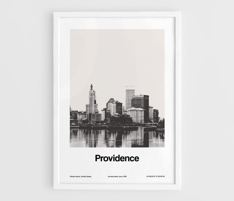 Op de afbeelding: Een zwart-witfoto van de skyline van Providence, Rhode Island. De stad wordt getoond met gebouwen die in het water worden weerspiegeld. De tekst "Providence" is onder de afbeelding gedrukt, samen met de locatie van de stad en de datum van inlijving.