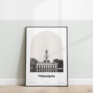 May include: A black and white photograph of Independence Hall in Philadelphia, Pennsylvania. The building is framed by a light brown arch. The text "Philadelphia" is below the building, with the text "Pennsylvania, United States" and "Founded 1682" below that.