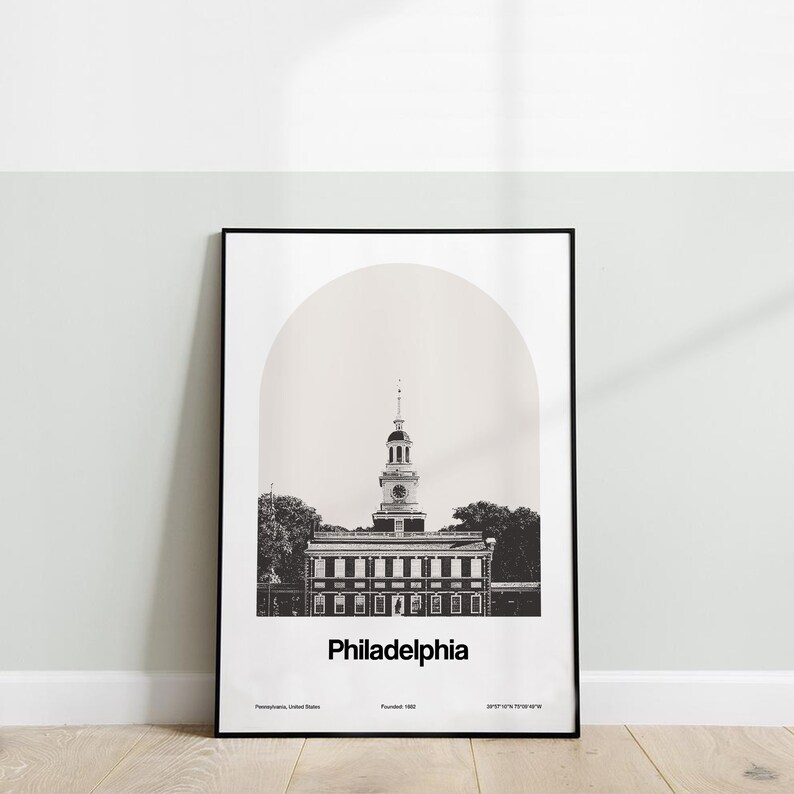 May include: A black and white photograph of Independence Hall in Philadelphia, Pennsylvania. The building is framed by a light brown arch. The text "Philadelphia" is below the building, with the text "Pennsylvania, United States" and "Founded 1682" below that.