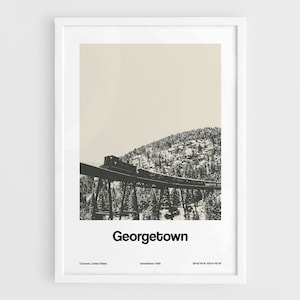 Peut inclure: Une illustration en noir et blanc d'un train traversant un pont en treillis dans un paysage montagneux enneigé. Le texte "Georgetown" est sous l'image, ainsi que le texte "Colorado, États-Unis, Établi en 1859, 39°24'47"N 105°51'16"W".