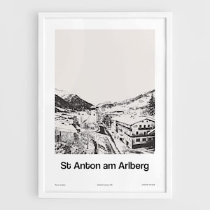 May include: Black and white framed print of St. Anton am Arlberg, Austria. The image depicts a snowy mountain village with buildings, a church, and surrounding mountains. The text "St Anton am Arlberg" is printed at the bottom.