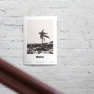 May include: Black and white minimalist poster with a palm tree silhouette on a beach. The poster has the word "Mexico" printed at the bottom and the text "Capital: Mexico City, Independence: 16 September 1810".