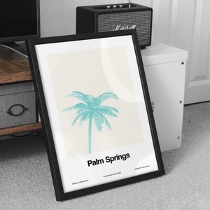 Pu&ograve; includere: Un poster incorniciato in nero con sfondo bianco e un'illustrazione di palma turchese. Il testo "Palm Springs" &egrave; stampato in nero nella parte inferiore del poster. Il testo "California, United States" e "Incorporated April 26, 1938" &egrave; stampato in nero pi&ugrave; piccolo sotto il testo principale.