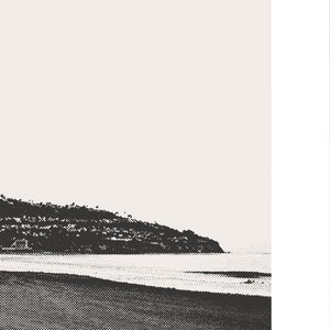 Pode incluir: Uma fotografia a preto e branco de uma praia com uma costa rochosa e um mar calmo.